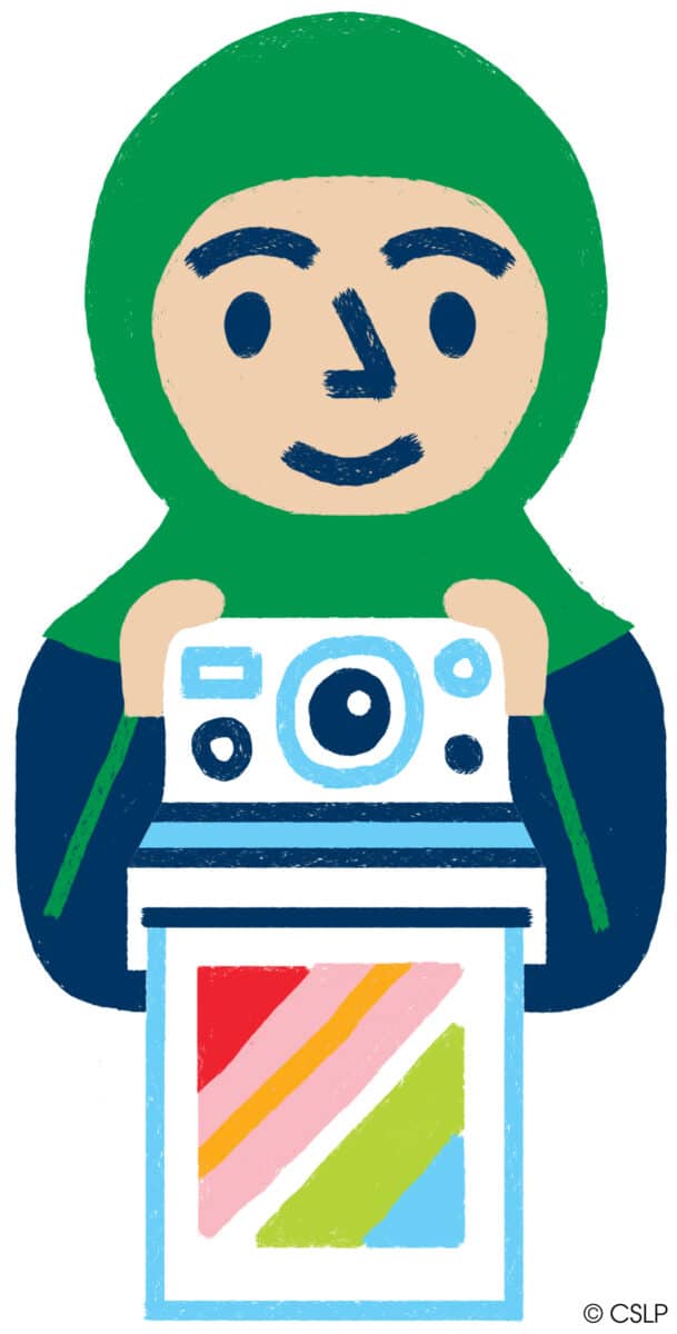 Person with blue and green hoodie holding an instant camera with a rainbow colored picture coming out