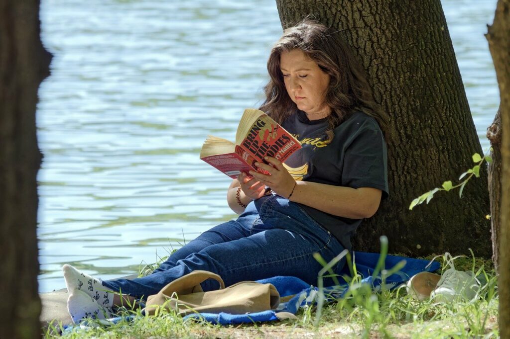 woman reading, book, sitting, lakeshore, leaning, tree trunk, relaxation, nature, park, lifestyle
