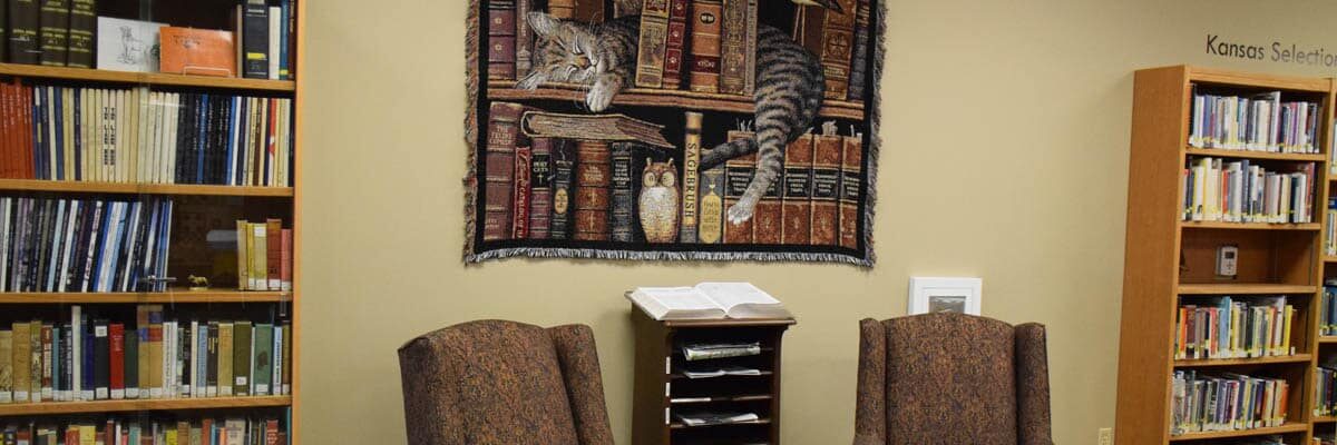 Public library with a cat tapestry, newspapers and two armchairs